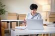 © matinee - Small business owner smiling while processing customer orders at a workspace.  E-commerce concept.