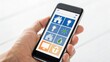 © Johnnii - A hand is holding a smartphone displaying a home automation app with icons for lights, temperature, water, and energy control.