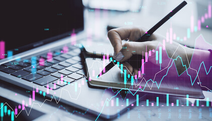 Poster - Financial trader writing in notebook with digital forex and stock market graphs overlayed on laptop background in modern office environment.