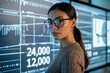 © Pixels Pictures - A professional headshot of a woman data analyst in a modern office setting. The subject wears black-rimmed glasses and a gray ribbed sweater, with dark hair pulled back in a ponytail.