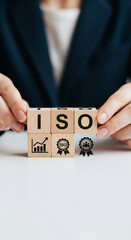 Poster - Close-up of hands arranging wooden cubes spelling ISO, with growth chart and award icons symbolizing quality management and business success