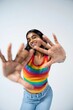 © Snap Halo - Portrait of a smiling woman in rainbow striped tank top posing with hands forward happy