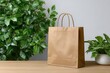 © Pixan - A brown paper shopping bag with handles stands on a wooden surface next to lush green plants