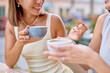 © we.bond.creations - Two female friends are sharing a moment together at an outdoor cafe, enjoying coffee and engaging in conversation