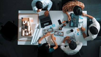 Poster - Top view of smart architect engineer writing at blueprint while sitting at meeting table with house model and laptop. Skilled manager working and taking about about building structure. Alimentation.