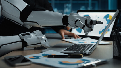Poster - A modern office scene featuring a robotic hand engaged with a laptop, symbolizing the convergence of technology and teamwork in innovative workspaces.Noogenesis