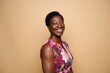 © Lens Focus - Portrait of smiling african american woman in floral dress against beige backdrop