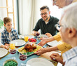 © Lumos sp - Happy multi-generation family gathering around dining table and having fun during a lunch or dinner on holiday or weekend