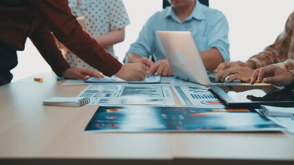 Poster - A diverse team engages in a dynamic business meeting, collaborating over laptops and documents while discussing strategies and analyzing data in a modern office environment. SACTR