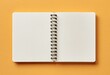 © Mhammad - Open spiral-bound notebook on orange background