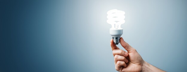 Poster - Hand holding illuminated energy-saving light bulb against blue background with space for text, symbolizing innovation and energy concept.