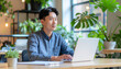 © Dreamera - Hombre trabajando con una laptop y plantas alrededor, ambiente moderno y relajado de oficina