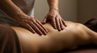 © muharsakas - Closeup of a person receiving a back massage with two hands on their lower back in a dimly lit room