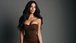 © PhotoLuxeStudio - Elegant woman with long black hair wearing strapless brown dress posing confidently against dark background