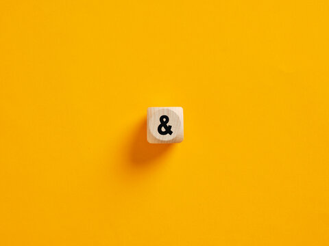 Wooden cube showing an ampersand sign on a yellow background