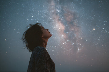Wall Mural - silhouette of a young woman looking up at the milky way in a starry night sky, evoking a sense of wo