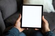 © Igor - Man on sofa holding blank white tablet screen