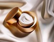 © Nicholas - close up of luxury skincare cream jar with golden lid placed on white silk fabric with soft shadows