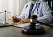 © Aleya - A doctor reviews legal documents with a gavel on the desk in the office