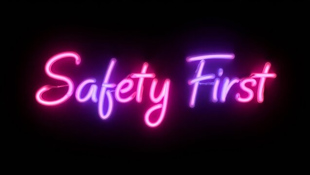 Safety first glowing colorful neon cursive calligraphy lettering on plain black dark background.