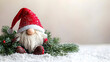 © SUDARNO - Festive gnome figurine nestled in snowy greenery.  Soft, plush gnome in a red hat sits amongst pine boughs and faux snow.  A charming Christmas decoration