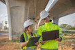 © reewungjunerr - Two engineers discuss about work at the site of large bridge under construction,Management consulting people discussion with engineers about the progress and construction planning of highway