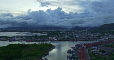 Wall Mural - Aerial view of Fishing boats sail down the river back to the pier under the cloudy sky of the sunset. The large fishing port supports large fishing boats, which are important to Phuket's economy