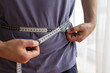 © Point of view - man  measures waist size. concept of fighting excess weight and obesity, social standards of beauty, active lifestyle
