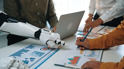Poster - A humanoid robot collaborates with professionals in an office, pointing at data charts and graphs, showcasing the integration of technology in business analysis.Noogenesis