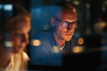 Poster - Employee collaborates with colleague during late-night project in a modern office environment with a focus on teamwork and technology