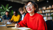© perfectlab - Young Asian woman in red sweater taking notes during meeting in creative office space