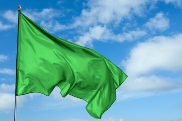 Wall Mural - green flag waving against blue sky outdoors