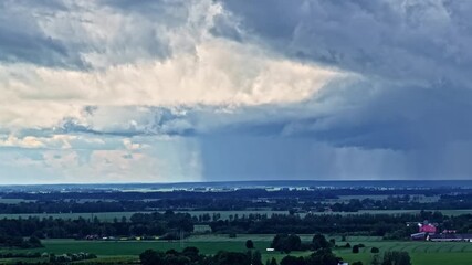 Wall Mural - Aerial rising view reveals dark storm clouds sweeping over lush green fields and forests near Jelgava, Latvia, under dramatic skies.