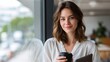 © AspctStyle - Confident young woman standing by office window holding coffee cup and tablet, dressed in white blouse, smiling softly in modern workspace with natural daylight and blurred city view outside
