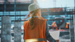 © Videophilia - Female engineer holding blueprint supervising construction site progress