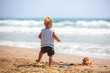 © vvvita - A small baby boy walks along the beach on a sunny summer day