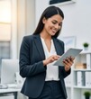 © picturehome - Happy busy female professional executive using tab standing in office. Smiling young adult Hispanic businesswoman leader or entrepreneur, company worker using tablet at work. Vertical photo.