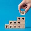 © ivatekstudio - Achieving the Aim: An upward arrow represents growth and progress with target. Hand places last block with target mark on stairs.