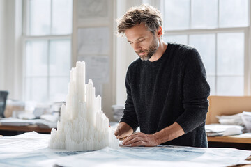 Poster - Focused designer crafting a detailed architectural model in bright studio. Conceptual for innovation, planning, construction, and artistic pursuits.