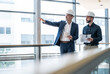 © Westend61 - Architects in safety helmets consulting on a project in modern office