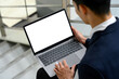 © Prathankarnpap - Male office worker sitting on stairs near a building, holding laptop with a white screen
