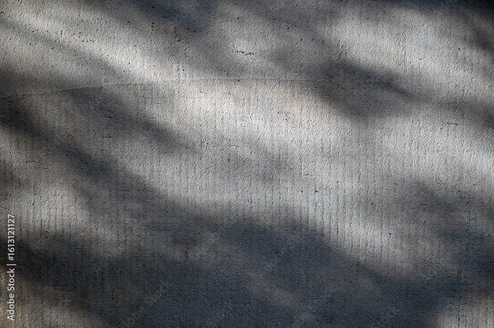 Shadows cast on textured concrete surface during late afternoon light ...