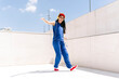 © VISTA by Westend61 - Person dancing outdoors in blue outfit with red shoes and hat