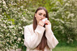 © New Africa - Woman with paper tissue suffering from seasonal pollen allergy near blossoming shrub on spring day
