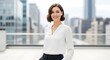 © Ingrida - Woman in white blouse smiling with city buildings background