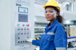 © AU USAnakul - Portrait of Hispanic female technician in safety gear operating control panel at modern manufacturing plant, smiling confidently at camera.