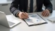 © 五行 阴阳 - Businessman analyzing financial charts with a pen and clipboard at a desk