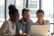 © Wang - Three people smiling at a laptop in a well-lit office.