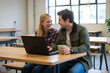 © Aleksei Solovev - A man and woman collaborating happily over a laptop in a casual workspace.