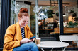 © TrueShot | Westend61 - Smiling woman using smart phone while sitting at cafe